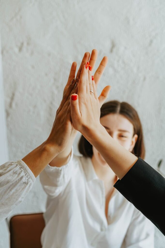pexels photo 8145343 A group of adults in a warm atmosphere celebrating teamwork with a high-five gesture.